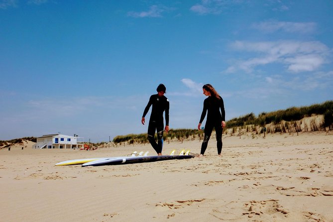 Surfers carrying boards down to the water at dusk on a Portuguese beach